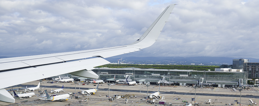 Vista aérea del ala de un avión sobre la pista y la terminal de un aeropuerto internacional.